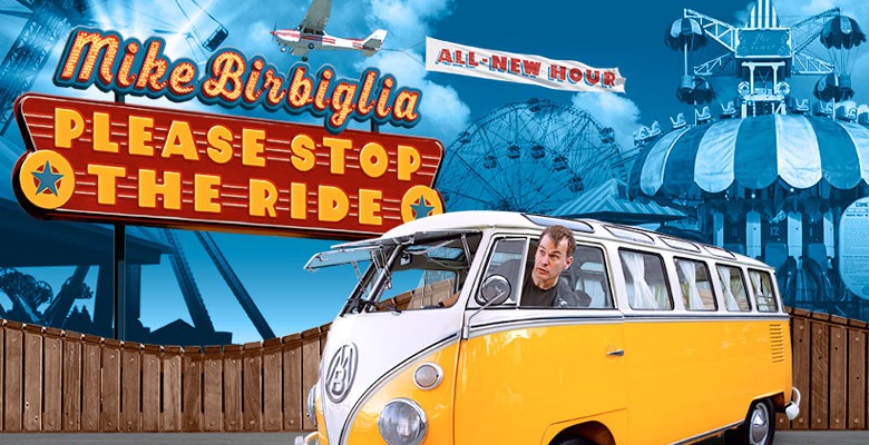 Photo of Mike Birbiglia in VW bus looking out window with carnival sign & rides in background