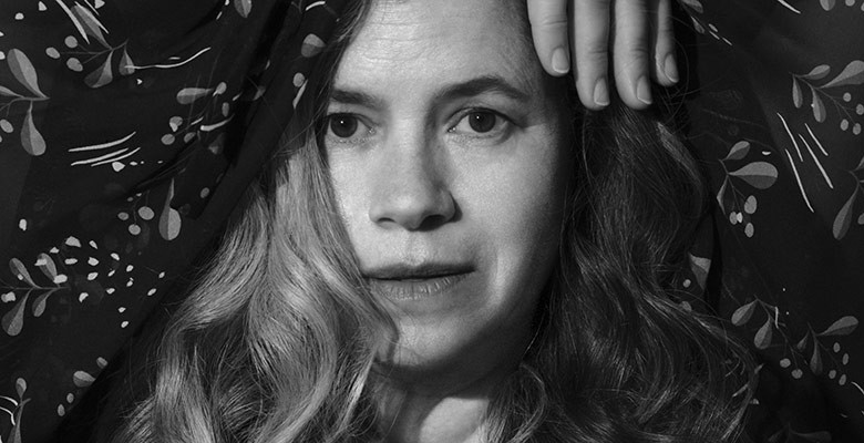 Black and white photo of Natalie Merchant - head shot with her hand over her head