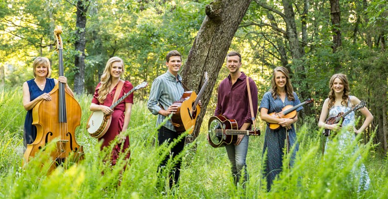 Photo image of the Petersens band members holding instruments in a nature setting