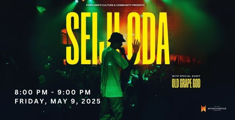 performer in bucket hat and tee with mic in one hand and other arm in air
