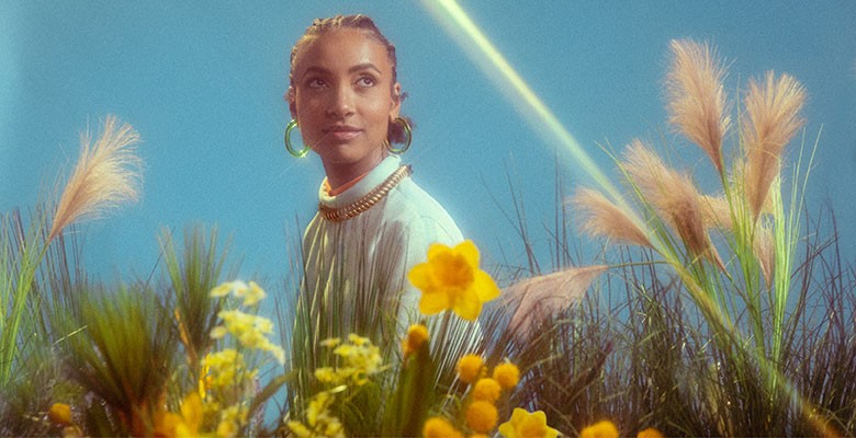 Photo of esperanza spalding sitting among tall grass