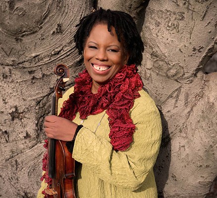 Photo of Regina Carter smiling and holding a violin.