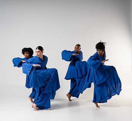 photo of four male and female dancers wearing blue robes