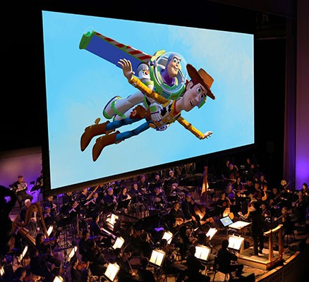 Photo of Toy Story scene (Woody and Buzz) being shown on screen with symphony