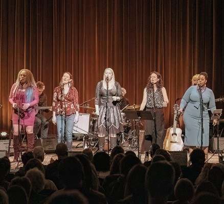 Photo of the women of She's Speaking performing together on stage
