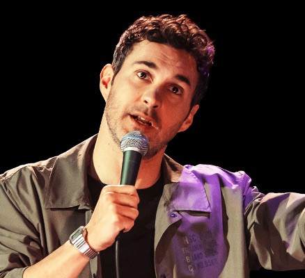 Photo of Mark Normand holding microphone, performing