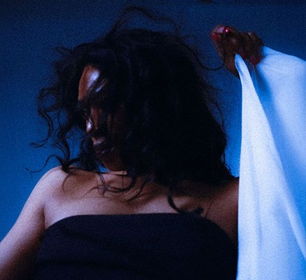 black woman looking to left holding white sheet