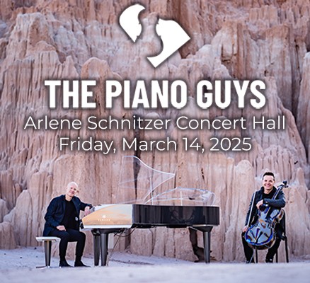 The Piano Guys sitting with a grand piano and cello in front of a rock wall