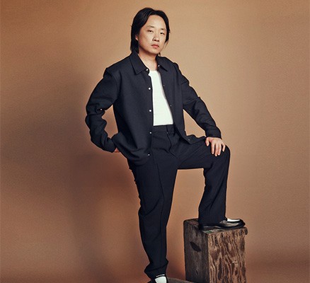 A photo of Jimmy O Yang standing with one foot raised on a box as he looks into the camera