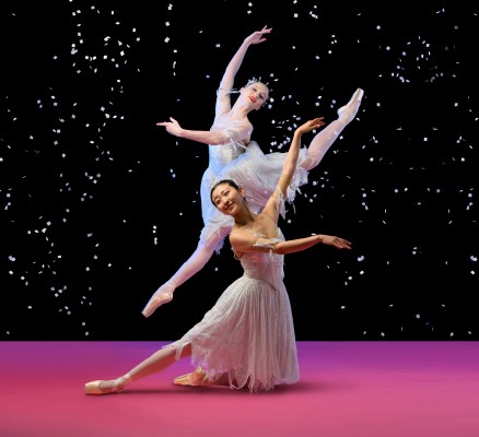 Photo of two ballet dancers on stage in front of a starry backdrop of The Nutcracker