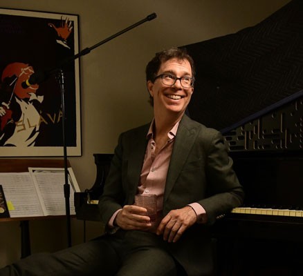 Photo of Ben Folds sitting with his back to a piano