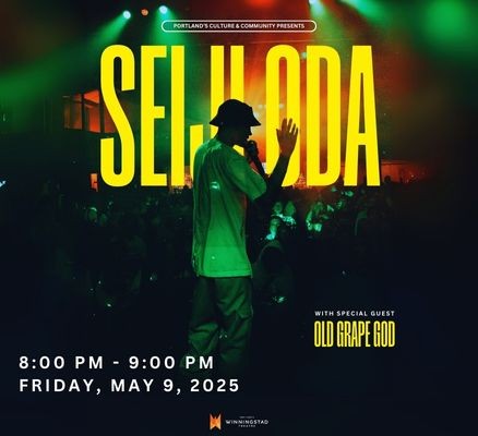 performer in bucket hat and tee with mic in one hand and other arm in air