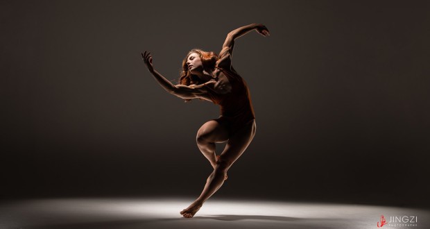 Photo of dancer in pose, in low, contrasted light. Photo credit: Jingzi Zhao.