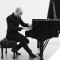 Black & white photo of Aaron Diehl playing piano on a white stage.