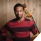 Photo of Xavier Foley holding a double bass against a wood grain background.