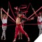 Main performer surrounded by back up performers with red ribbon