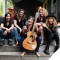 Photo of Ashley Flynn & The Riveters sitting together on porch steps, smiling