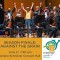 Photo of MYS musicians and conductor standing on stage, holding raised hands