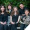 Photo of MYS musicians sitting on bench with conductor standing behind them
