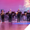 brass players standing on stage in front of purple backdrop