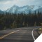 Photo of a curving road with snowy mountain peaks in the background
